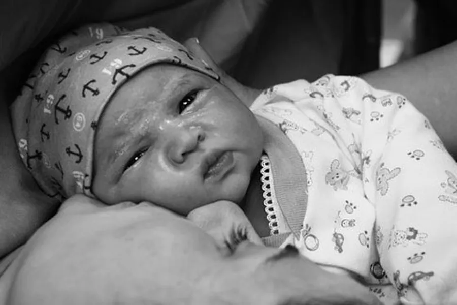 Svart-kvitt bilde av ein nyfødd baby saman med mor