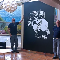 bilde av to menn som står ved sidan av eit stort bilde av to personar som omfavnar kvarandre