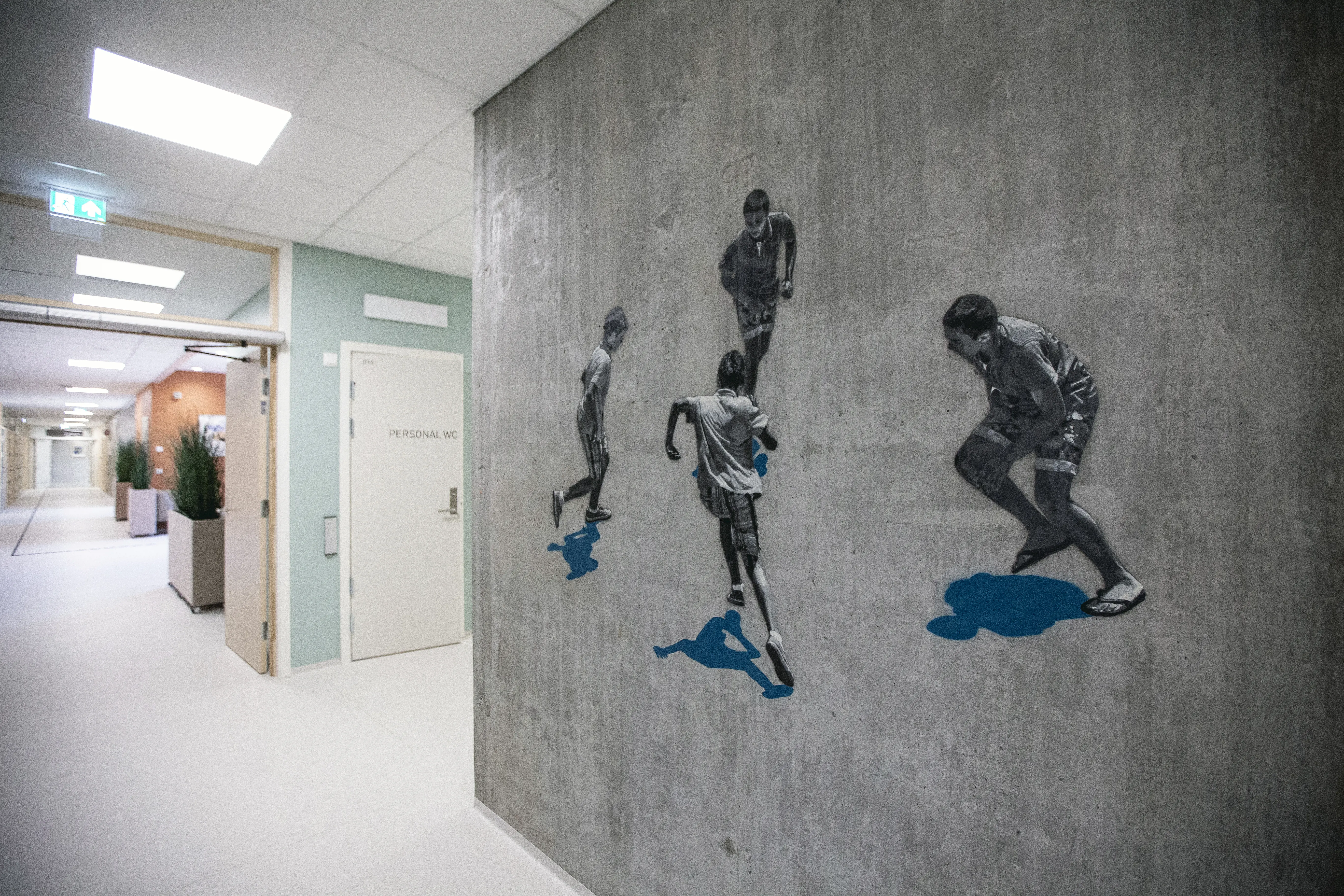 murvegg i ein korridor med ein betongvegg med kunstverk av fire gutar som leikar
